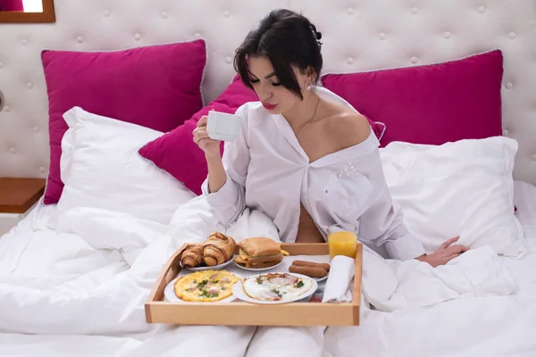 年轻女子在床上吃早餐 — 图库照片