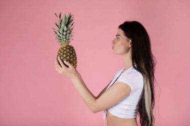 güzel seksi genç kız ananas ile pembe bir arka plan üzerinde duran.