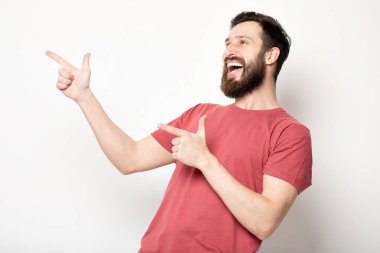 Gri arka planda izole genç şaşkın sakallı adam portresi