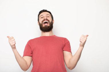 Gri arka planda izole genç şaşkın sakallı adam portresi