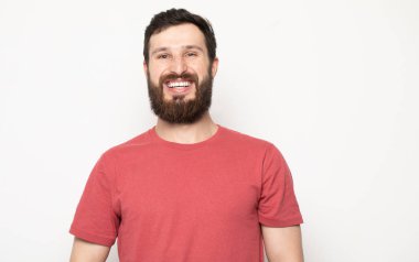 Gri arka planda izole genç şaşkın sakallı adam portresi