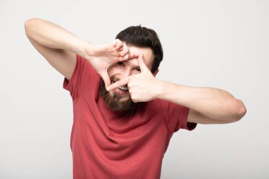 Gri arka planda izole genç şaşkın sakallı adam portresi