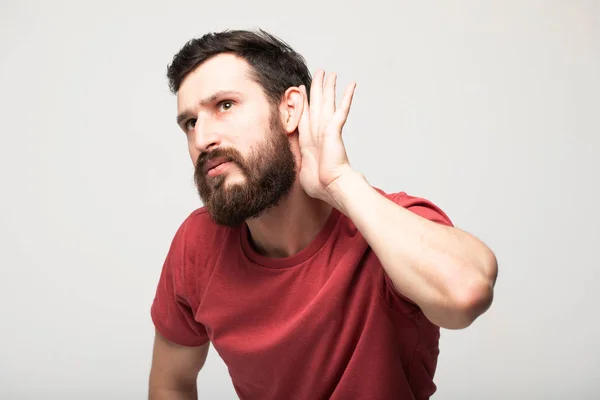 Skäggiga Man Lyssnar Tittar Gesten Hand Bakom Örat Isolerad Grå — Stockfoto