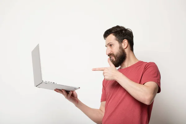 Молодий Бородатий Чоловік Дивиться Екран Ноутбука Руках Стоїть Ізольовано Світлому — стокове фото