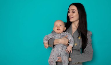 Yeni doğan çocuğunu kucağına tutan genç bir anne. Kadın ve yeni doğan çocuk renk arka plan üzerinde dinlenmek. Anne emziren bebek. Evde aile. Yeni doğan oğluyla oynayan genç anne