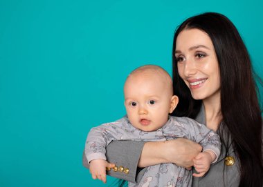 Yeni doğan çocuğunu kucağına tutan genç bir anne. Kadın ve yeni doğan çocuk renk arka plan üzerinde dinlenmek. Anne emziren bebek. Evde aile. Yeni doğan oğluyla oynayan genç anne