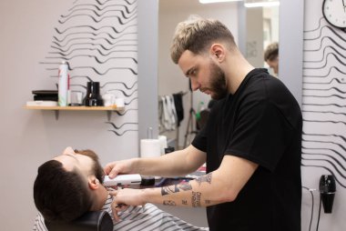 Sakal ve bıyık kuaför dükkanında bakım sırasında istemci