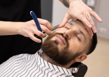 Sakal ve bıyık kuaför dükkanında bakım sırasında istemci