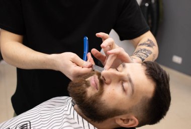 Berberin keskin bir jiletle traş edişının yakın çekimi..