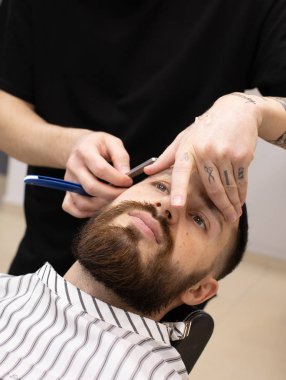 Berberin keskin bir jiletle traş edişının yakın çekimi..