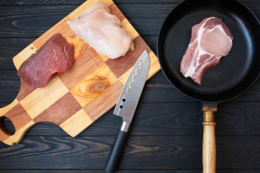 Kasap bıçağı ile ahşap arka plan üzerinde kemik, domuz eti ve tavuk fileto çiğ et eti Çeşitleri, üst görünümü