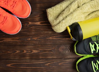 Spor malzemeleri - spor ayakkabı, su6 havlu. Ahşap zeminde spor arka plan, üst görünüm .