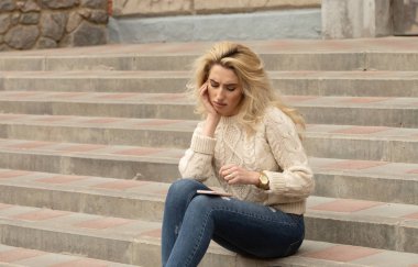 Yaz günü ve holding cep telefonu üzerinde bağdaş ile sokak merdivenlerde oturan güzel şık kadın görüntüsünü