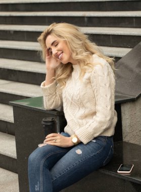 Yaz günü ve holding cep telefonu üzerinde bağdaş ile sokak merdivenlerde oturan güzel şık kadın görüntüsünü