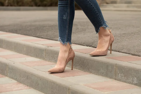 Close up of slim legs of woman wearing high heel shoes.