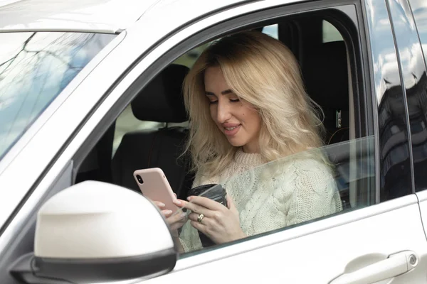 Hermosa Mujer Está Sentada Conduciendo Coche Ella Sostiene Teléfono Móvil — Foto de Stock