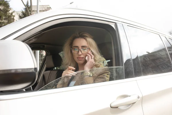 Hermosa Mujer Está Sentada Conduciendo Coche Ella Sostiene Teléfono Móvil — Foto de Stock