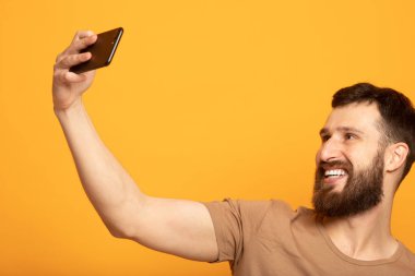 Selfie sarı arka plana alarak neşeli bir sakallı adam portresi kapatın