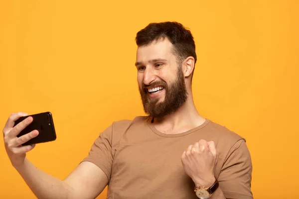 Retrato Hombre Emocionado Pie Sobre Fondo Amarillo Sosteniendo Teléfono Móvil — Foto de Stock