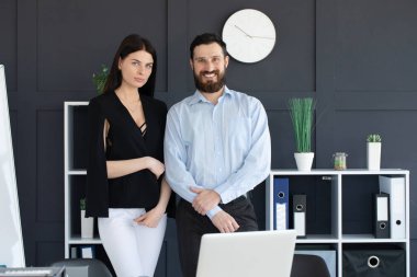 çekici başarılı iş ortakları ile bir genç erkek ve kadın arka arkaya güvenle kameraya gülümseyen katlanmış silah ile poz 