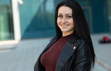 Açık poz uzun esmer saçlı Inanılmaz neşeli güzel kız. Deri ceket, esmer saçlı. Moda sokak stile portre.