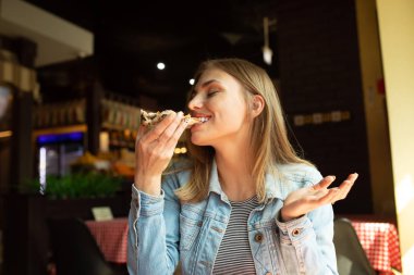 Restoranda pizza yiyen kot ceket komik sarışın kız.