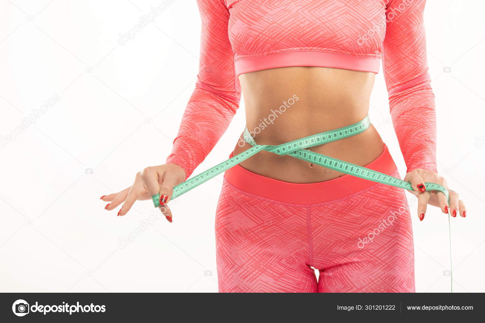 Cropped view of young woman measuring her waist with tape measure
