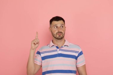 Genç adam pembe arka planda poz parmak ile işaret