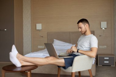 Genç adam Freelancer çalışan koltukta oturan dizüstü bilgisayar ile