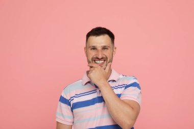 Genç neşeli adam pembe arka plan üzerinde poz