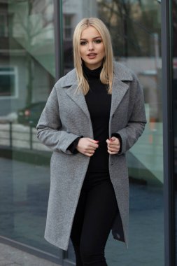 Gri ceketli zarif sarışın kadın şehirde poz, arka planda modern bina.