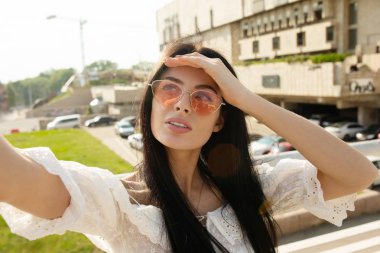 Kentsel arka planda selfie yapan ince esmer kadın portresi