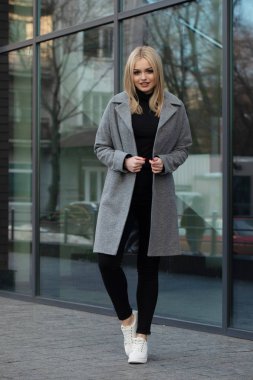 Gri ceketli zarif sarışın kadın şehirde poz, arka planda modern bina.