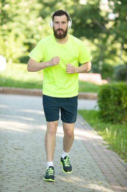 Parkta kulaklık ve spor giyim eğitimi genç sakallı adam