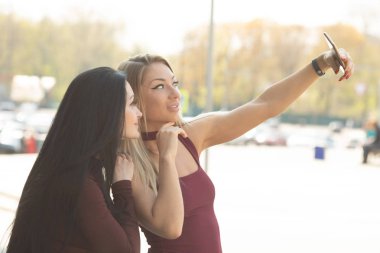 Dışarıda selfie çeken iki güzel genç kadın.