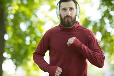 Parkta kulaklık ve spor giyim eğitimi genç sakallı adam