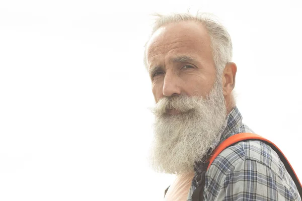 カジュアルな服と赤いバックパックであごひげと口ひげを持つヒップスターの老人が街を歩く — ストック写真