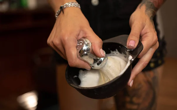 Shaving accessories in barber hand. Foam brush.