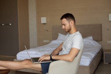 Genç adam Freelancer çalışan koltukta oturan dizüstü bilgisayar ile