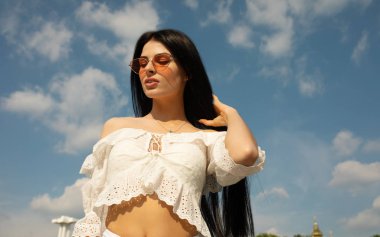 Mavi gökyüzü arka planda poz veren ince esmer kadın portresi