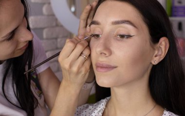 Makyaj sanatçı göz farları uygular. Makyaj ustasının eli, model gözleri boyama.