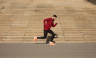 Merdiven arka planda çalışan spor giyim genç sakallı adam