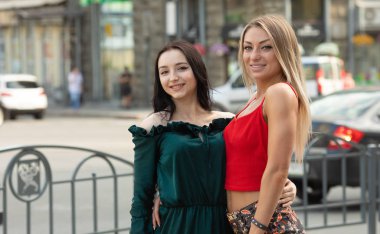 İki çekici genç kız arkadaş bir arada ve kamera önünde poz veriyor. Esmer ve sarışın kadınlar birlikte eğleniyorlar.