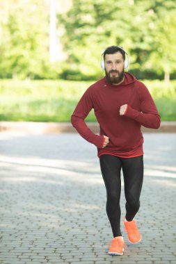 Parkta kulaklık ve spor giyim eğitimi genç sakallı adam