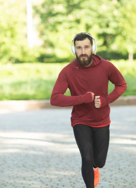 Parkta kulaklık ve spor giyim eğitimi genç sakallı adam