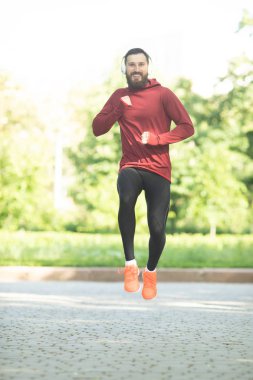 Parkta kulaklık ve spor giyim eğitimi genç sakallı adam