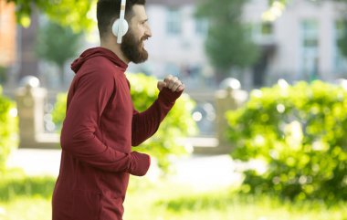 Parkta kulaklık ve spor giyim eğitimi genç sakallı adam