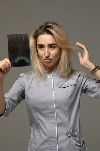 灰色の背景にレントゲン写真を持つ医師の女性 — ストック写真