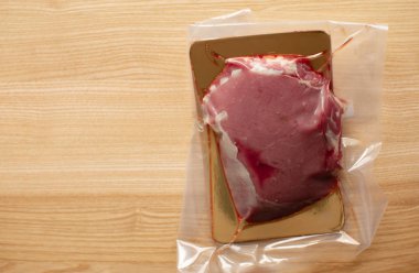 Süpürgeyle paketlenmiş çiğ et, tahtadan yapılmış biftekler.