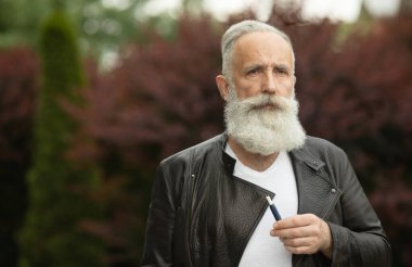 Elektronik Sigara Teknolojisi. Tütün IQOS sistemi. Sakallı yaşlı bir adamın elektrikli hibrit sigarayla ısıtma yastığını içerken yakın plan fotoğrafı..